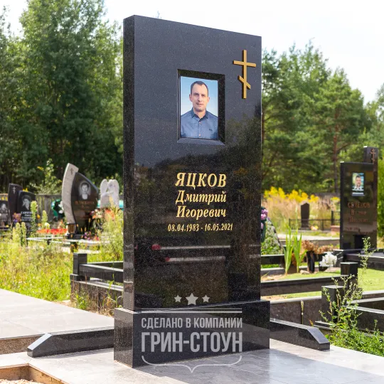 Фото массивного мужского мемориала из черного гранита с нишей под фотомедальон и накладным православным крестом из бронзы