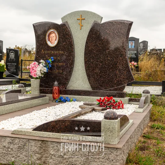 Изображение двойного семейного мемориала из темно-красного и серого камня. Две симметричные стелы неправильной формы и центральный элемент в контрасте.