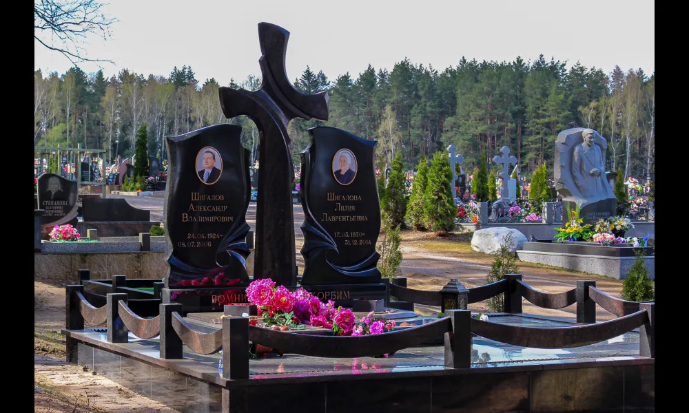 Семейный мемориал в составе двух стел и креста посередине. Гранитная ограда и плитка выдержаны в едином со стелами стиле.