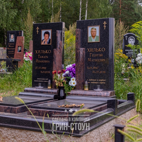 На фото двойной гранитный мемориал, украшенный бронзовыми аксессуарами. Столбики ограды выполнены с характерной 