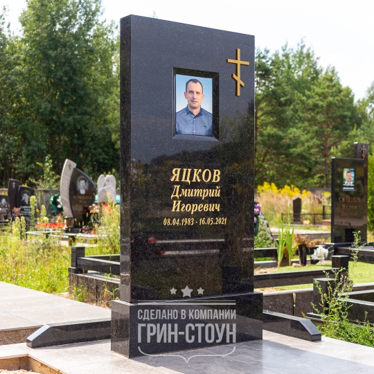 Фото массивного мужского мемориала из черного гранита с нишей под фотомедальон и накладным православным крестом из бронзы