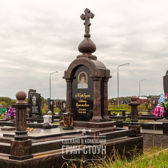 Фото элитного памятника на православную тематику: стелу в виде храма с куполом и колоннами венчает христианское распятие. Обратите внимание на массивные столбики ограды.