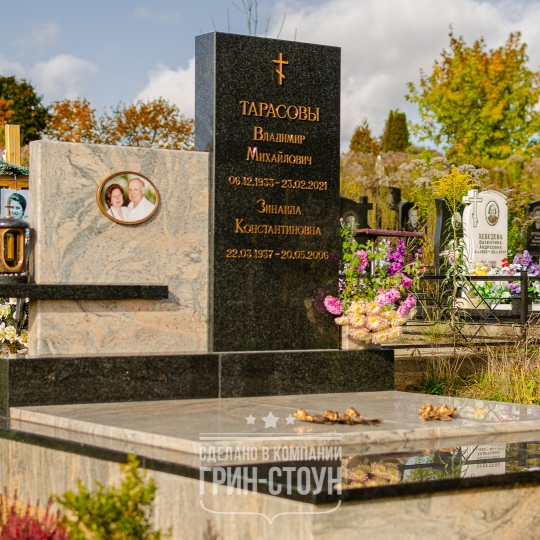 На фото двойной семейный мемориал из темного и светлого фактурного камня. В едином стиле выполнены стелы, надгробные плиты и облицовочная плитка.